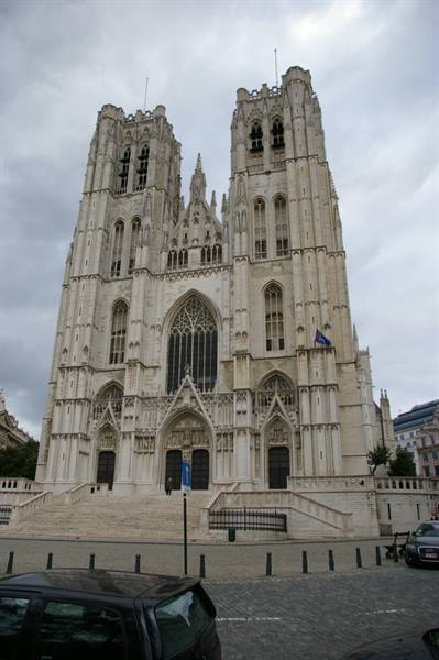Gothic stone facade of Brussels Cathedral with twin towers under cloudy sky