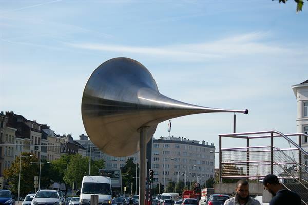 Horn-shaped steel sculpture towering over traffic below, Brussels