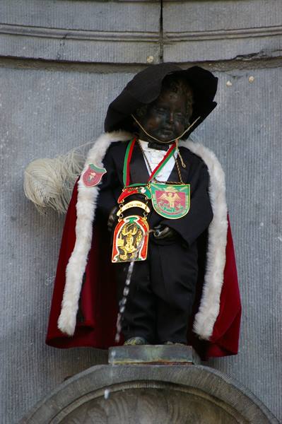 Manneken Pis in Brussels wearing black hat, red cloak and medals