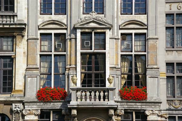 Stone facade with cross-paned windows, red geraniums and small stone balcony