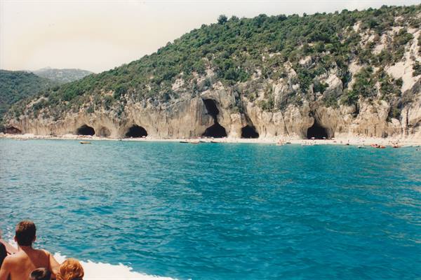 Tourists on a boat in front of caves in the rock at Cala Luna
