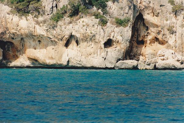Limestone cliffs with caves over turquoise sea, morning light