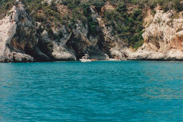 White boat anchored before limestone cliffs and turquoise water