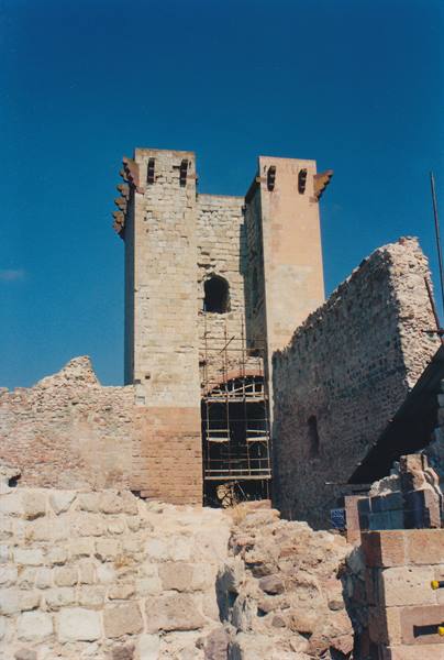 Stone castle tower with scaffolding among crumbling medieval walls under blue sky