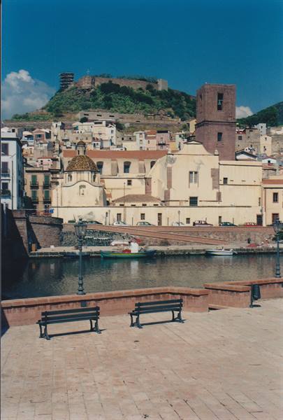 Benches along Bosa riverside, church and castle on the hill