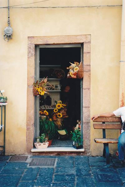 Dried flowers shop in stone doorway, wooden bench, yellow wall