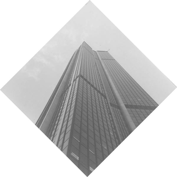 Glass skyscraper seen from below, dark facade against a grey sky