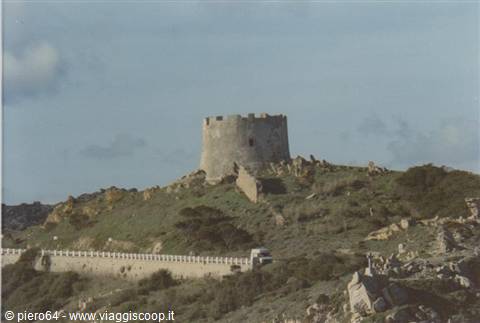 Ancient round stone tower on rocky hill, road with a car below
