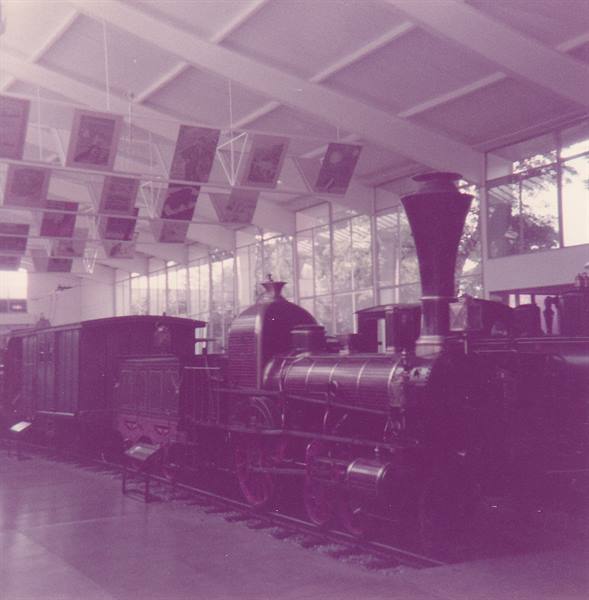 Vintage steam locomotive displayed in a museum hall with white beams