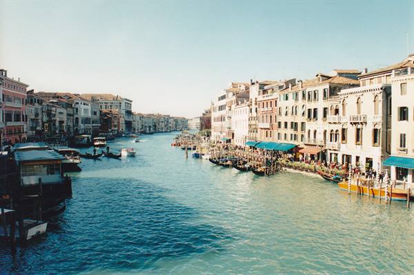 Gondolas and boats on Venice's Grand Canal, colorful palaces in sunlight