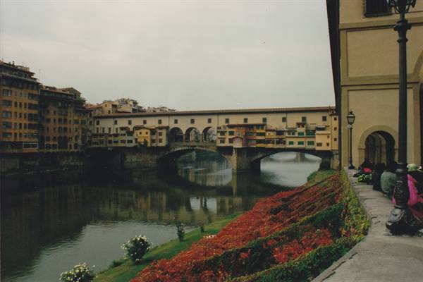 Ponte Vecchio over the Arno in Florence, red flowers along the bank