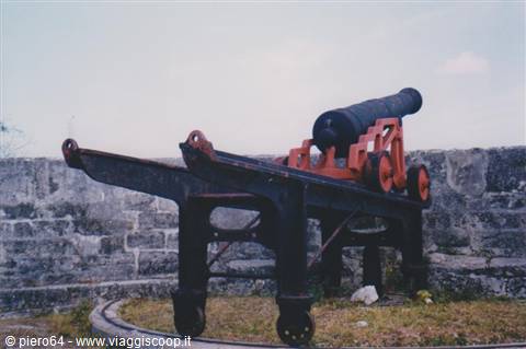Black cannon on red carriage, limestone fortress walls, grey sky