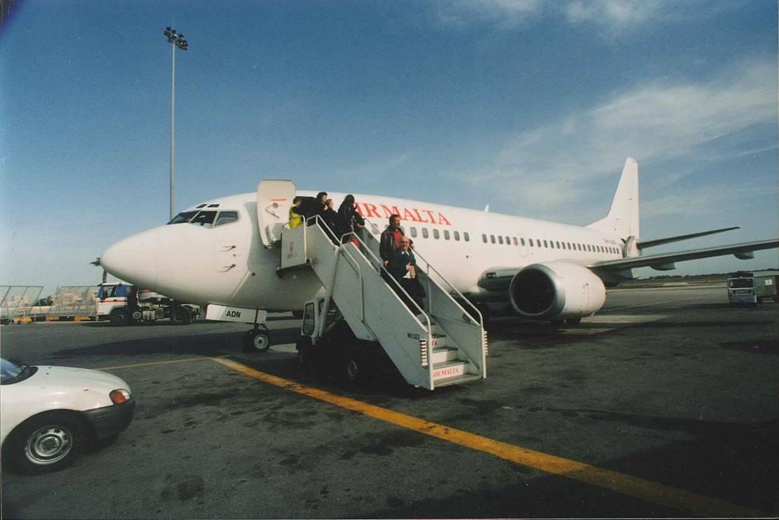 Passeggeri scendono da un aereo bianco Air Malta tramite scaletta mobile