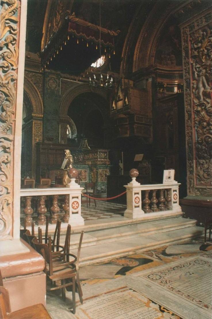 Interno di chiesa barocca: altare, balaustra marmorea, sedie di legno e pavimento intarsiato