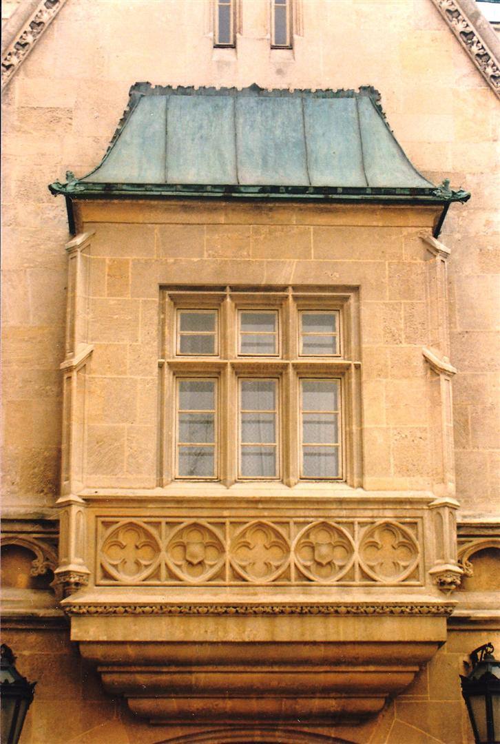 Balcone in pietra con fiori scolpiti e tetto in rame verde su facciata
