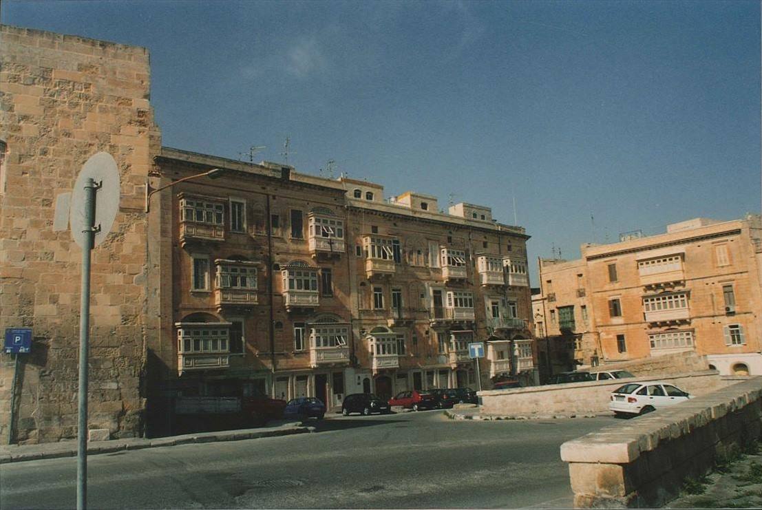 Palazzi in calcare ocra con balconi lignei a Valletta, strade con auto parcheggiate
