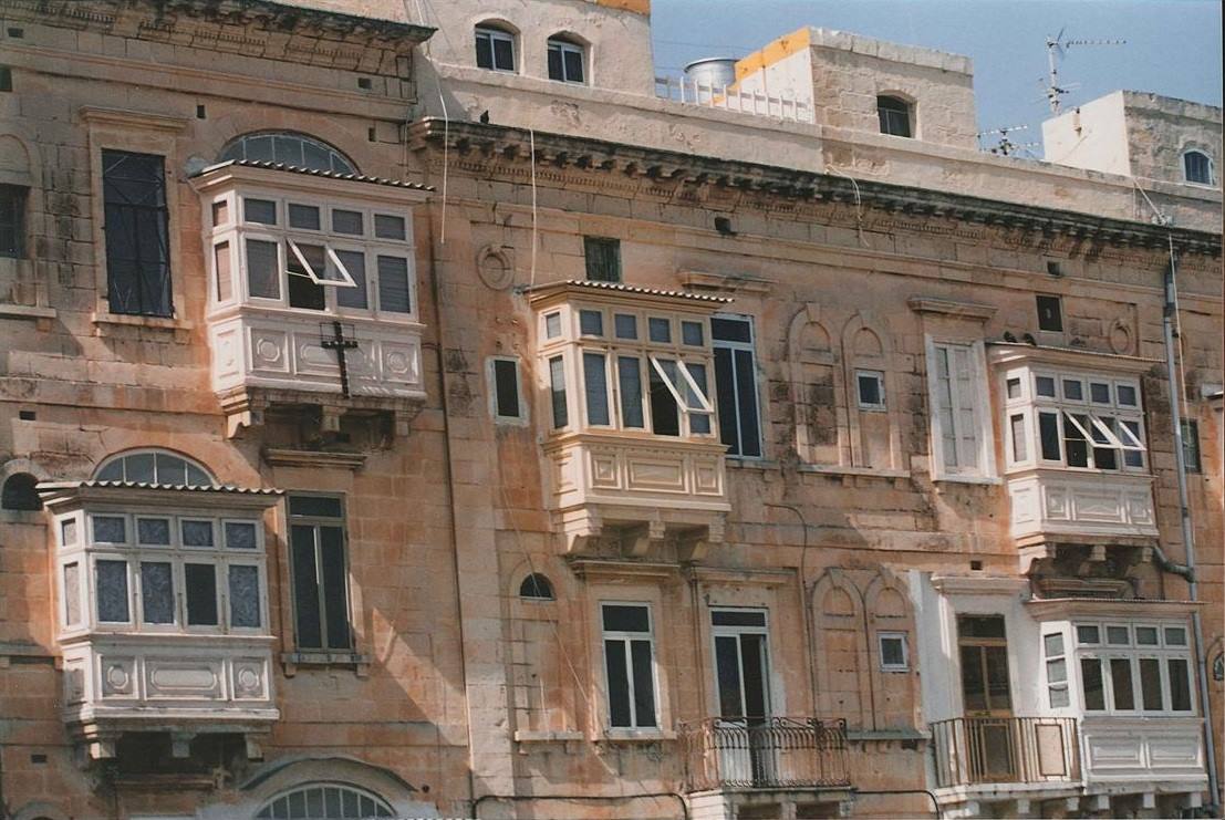 Balconi chiusi in legno su facciata in pietra arenaria maltese, luce solare