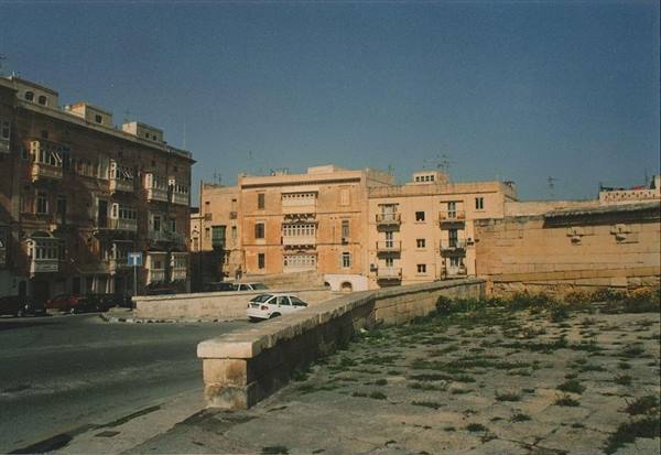 Limestone buildings with traditional balconies and old fortification walls in Malta