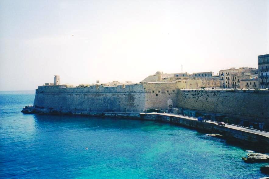 Mura bastionate in calcare su mare turchese, valletta fortificata affacciata sul porto