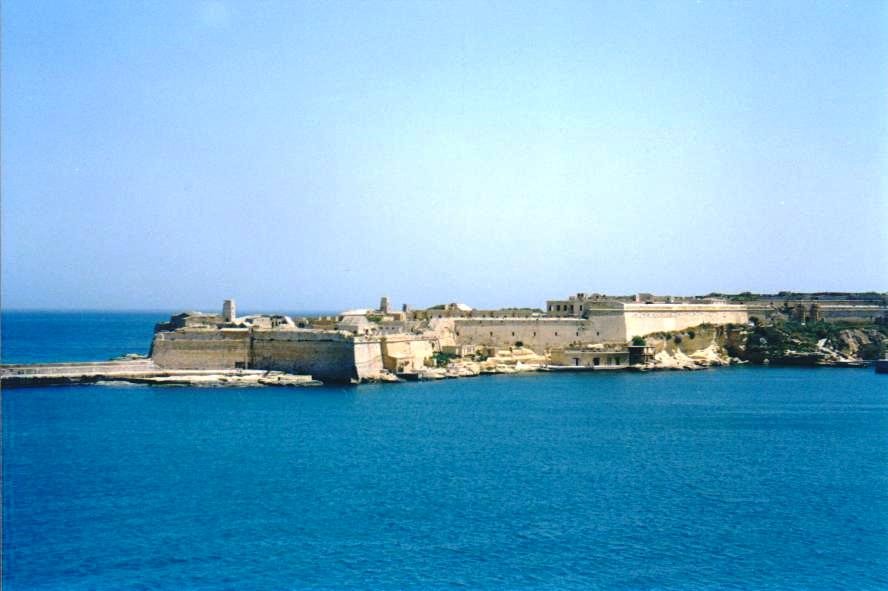 Mura fortificate in pietra calcarea sulla costa di Malta, mare azzurro