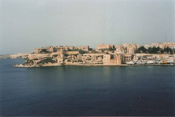 Limestone ramparts and ochre buildings on Valletta peninsula, boats in harbor
