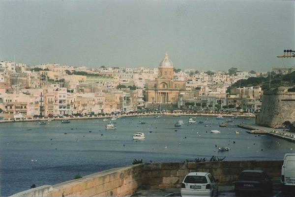 Boats moored at Marsamxett Harbour, domed church and limestone houses behind