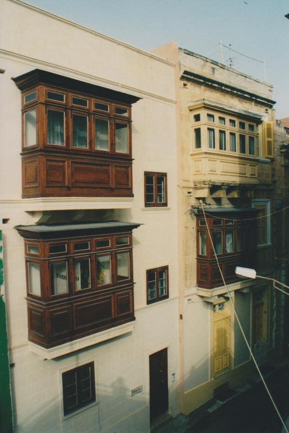 Balconi lignei maltesi sulle facciate color crema di Valletta, luce mattutina