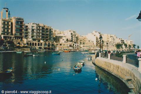 Boats moored in Spinola Bay, St Julian's, among limestone buildings