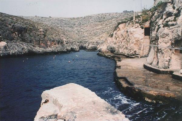 Blue water between limestone cliffs and rock-cut steps, Blue Grotto