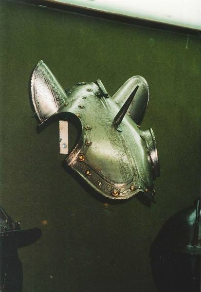 Engraved steel horse head armor displayed in a museum