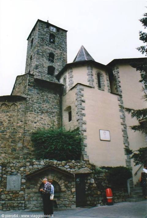 Stone church with Romanesque bell tower in Andorra la Vella, two tourists looking