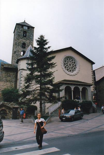 Sant Esteve church in Andorra la Vella, rose window and stone bell tower, pedestrians