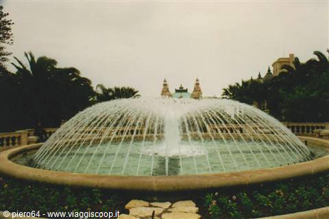 Circular fountain with arched water jets and palms in Catania