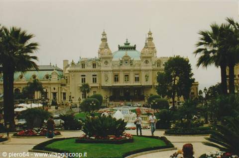 Tourists stroll through the garden in front of the Monte Carlo Casino among palms and flowers