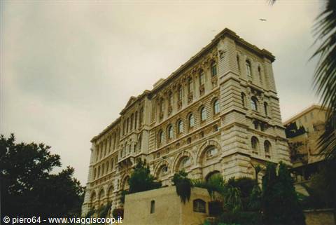 Oceanographic Museum of Monaco, pale stone facade among palm trees, cloudy sky