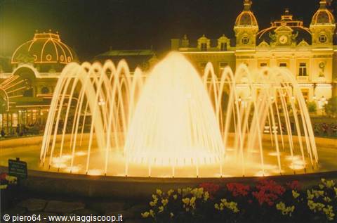 Illuminated fountain at night in front of Monte Carlo Casino, golden jets among flowers