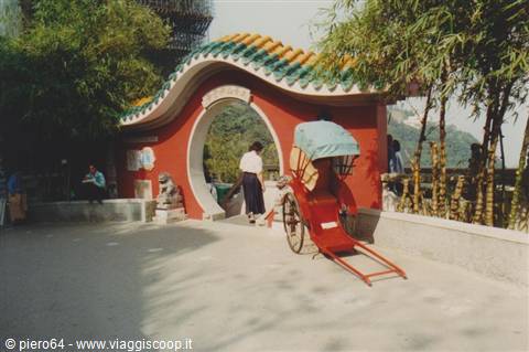 Red rickshaw in front of round red gateway with green tiled roof