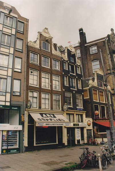 Brick facades with ornate gables in Amsterdam, parked bicycles under a grey sky