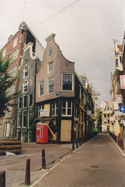 Curved-gable brick houses on an Amsterdam corner, dark facade, grey sky