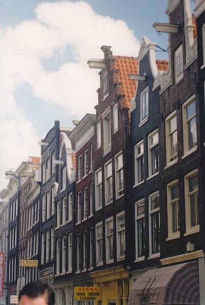 Narrow brick facades with curved gables and hoisting beams in Amsterdam