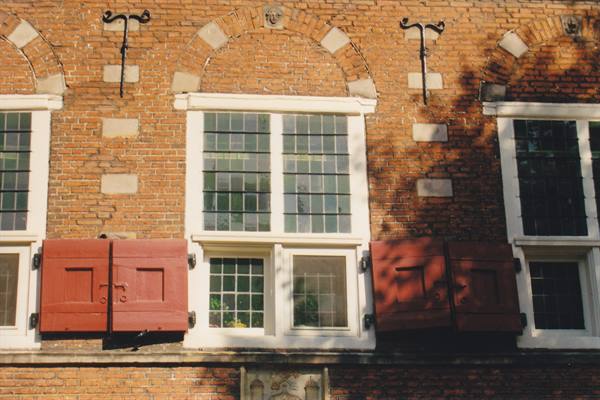 Red brick facade with white-framed windows and open red shutters