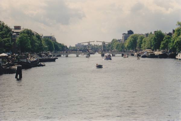 Boat on the Amstel in Amsterdam, drawbridge and moored boats among trees