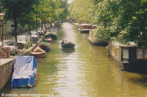 Motorboat among houseboats and covered boats along an Amsterdam canal