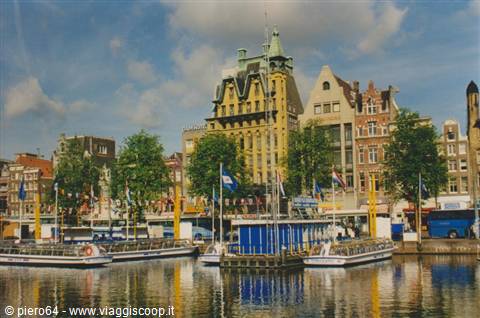Tour boats moored along an Amsterdam canal among historic gabled houses