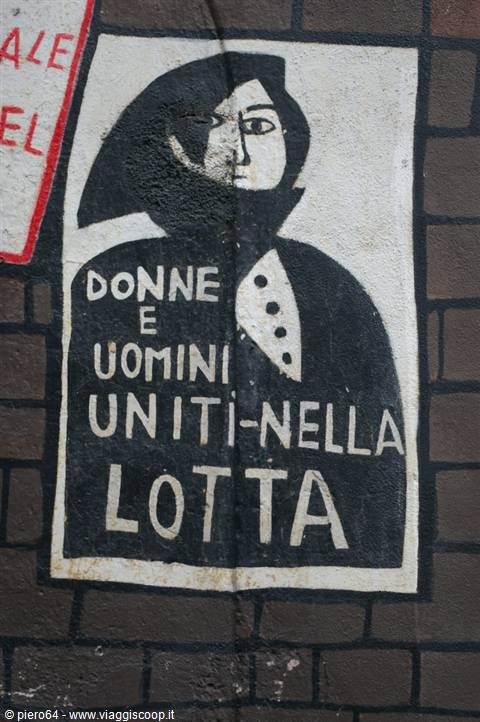 Mural painted on brick wall: black woman and man figure, writing 'Women and men united in struggle'