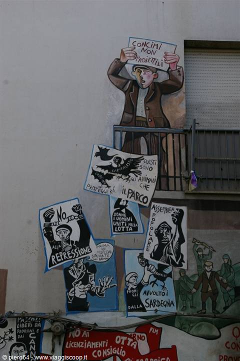Protest murals on building wall, man holding anti-bullets sign, Orgosolo