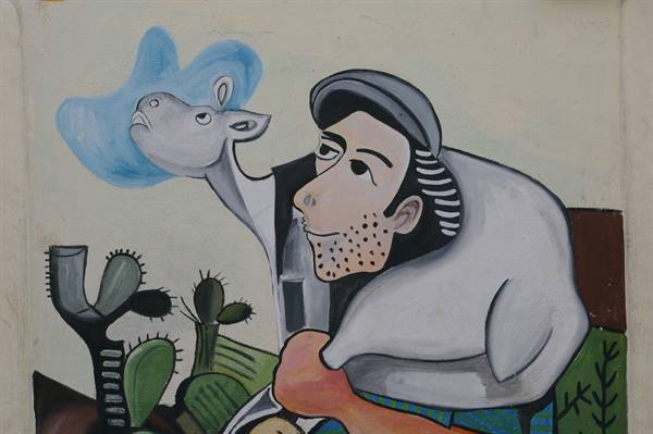 Mural of man with cap and donkey among prickly pears, vivid colors
