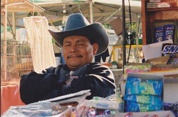 Man in cowboy hat behind a candy stall at the market
