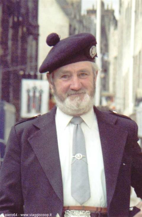Bearded man in black beret with pompon smiles on a city street
