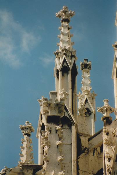 White marble Gothic spires with statues, Milan Cathedral against the blue sky
